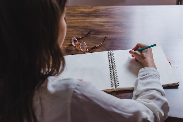 Vrouw schrijven in dagboek achteraanzicht