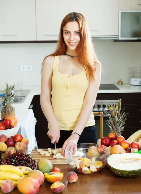 Vrouw snijden banaan voor fruitsalade