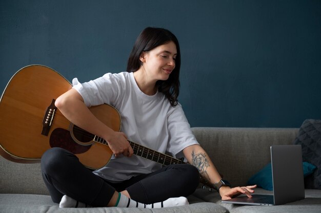 Vrouw speelt thuis gitaar tijdens quarantaine