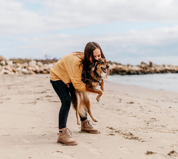 Vrouw spelen met hond op het strand