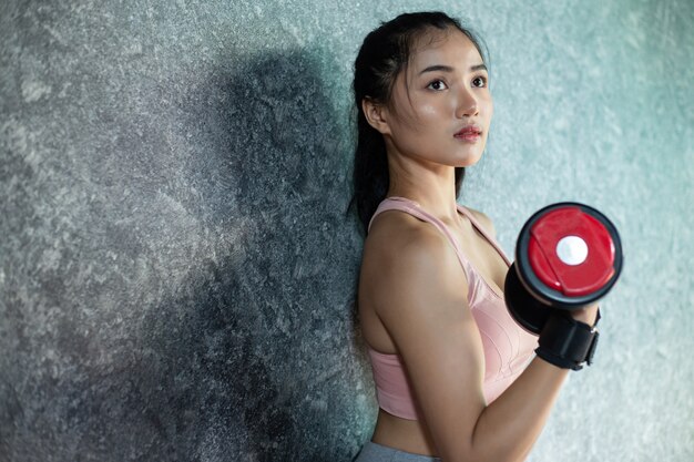 Vrouw status die met een rode domoor in de gymnastiek uitoefenen.