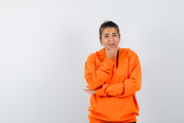 Vrouw steunt kin in oranje hoodie en kijkt hoopvol