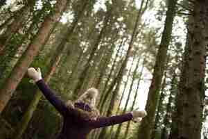 Gratis foto vrouw stond in het bos met haar armen wijd open