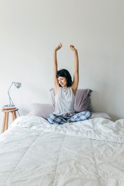 Vrouw strekt armen op bed