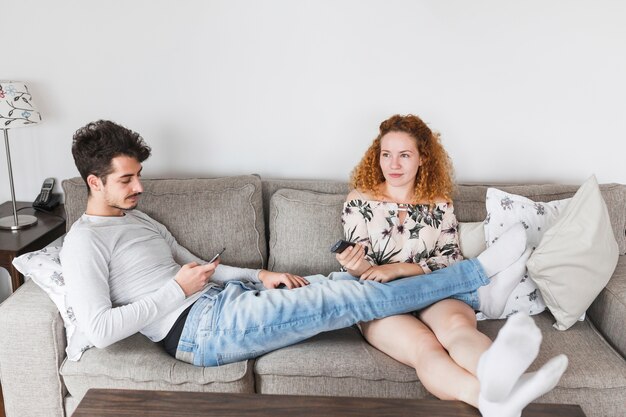 Vrouw televisie kijken terwijl haar man met behulp van smartphone