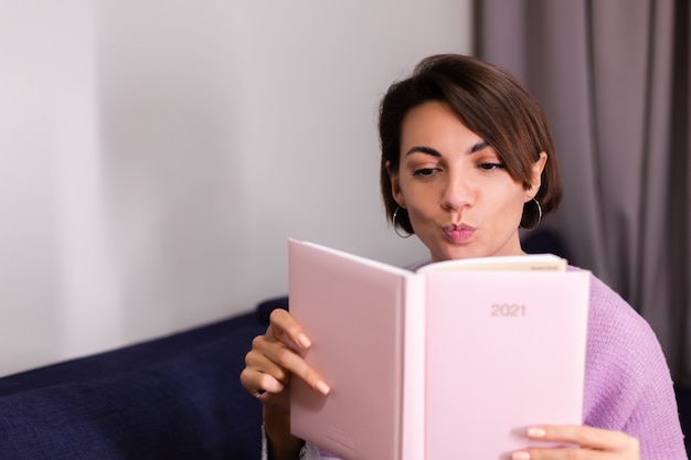 Vrouw thuis met kladblok notebook na te denken over plannen