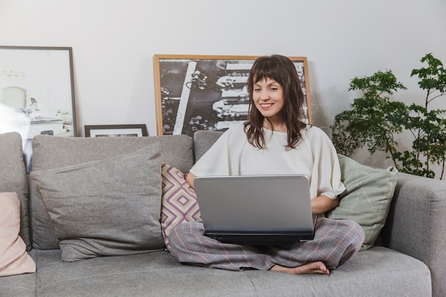 Vrouw thuis met laptop op sofa