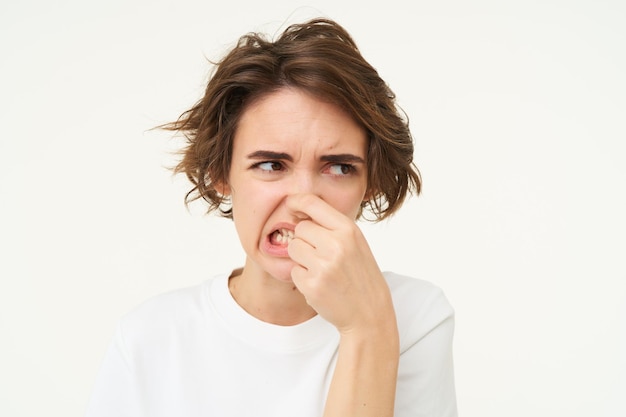 Vrouw toont afkeer, sluit haar neus voor stinkende stank, iets stinkt, staat over wit