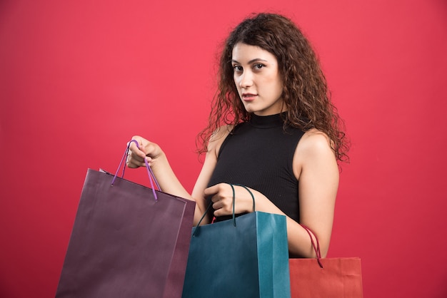 Vrouw toont haar nieuwe kleren kopen op rode achtergrond. Hoge kwaliteit foto