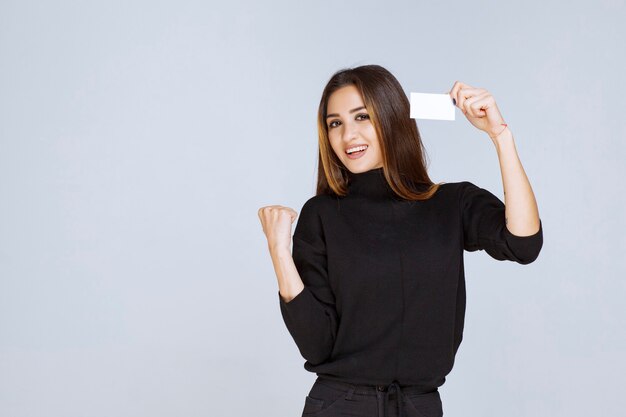 vrouw toont haar visitekaartje en vuist wijzend op haar succes.