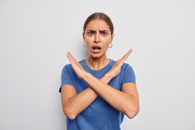 vrouw toont kruis stop gebaar zegt nee verbiedt slechte actie verwerpt iets draagt casual blauw t-shirt demonstreert taboe teken op wit