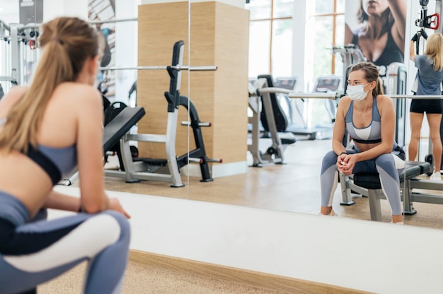 Vrouw training in de sportschool tijdens de pandemie met medisch masker