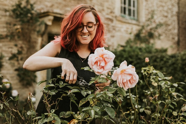 Vrouw tuinman roze snijden nam met tuin schaar toe