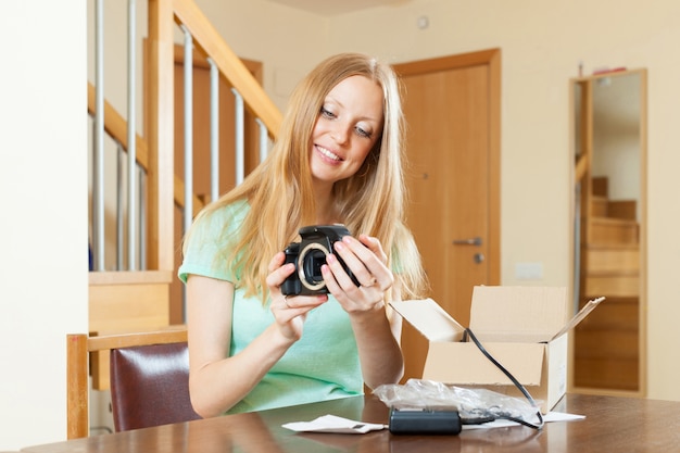 Vrouw uitpakken van nieuwe digitale camera thuis