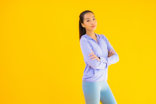 Vrouw van de portret de mooie jonge Aziatische sport klaar voor oefening op geel