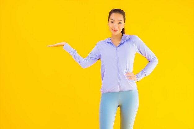 Vrouw van de portret de mooie jonge Aziatische sport klaar voor oefening op geel