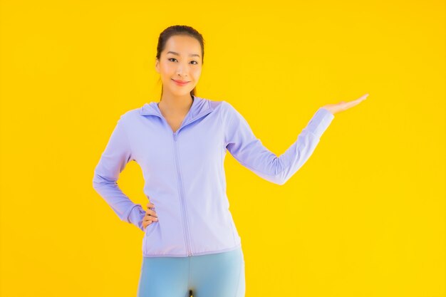 Vrouw van de portret de mooie jonge Aziatische sport klaar voor oefening op geel