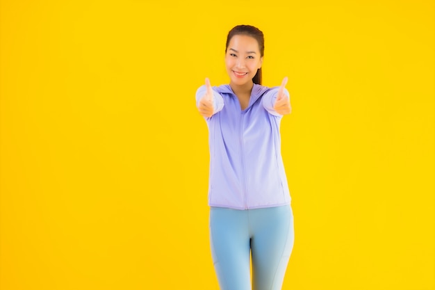 Vrouw van de portret de mooie jonge Aziatische sport klaar voor oefening op geel