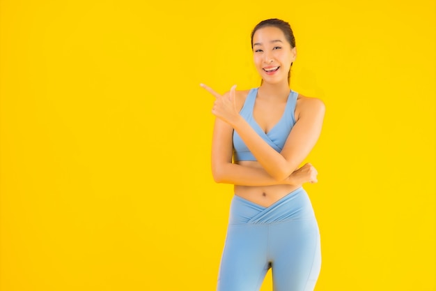 Vrouw van de portret de mooie jonge aziatische sport klaar voor oefening op geel