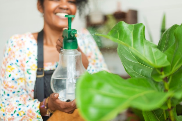 Vrouw vernevelt planten met een waterstraal in een plantenwinkel
