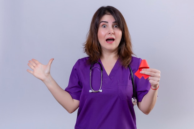 Vrouw verpleegster van middelbare leeftijd uniform dragen en met een stethoscoop met rood lint een symbool van de strijd tegen aids