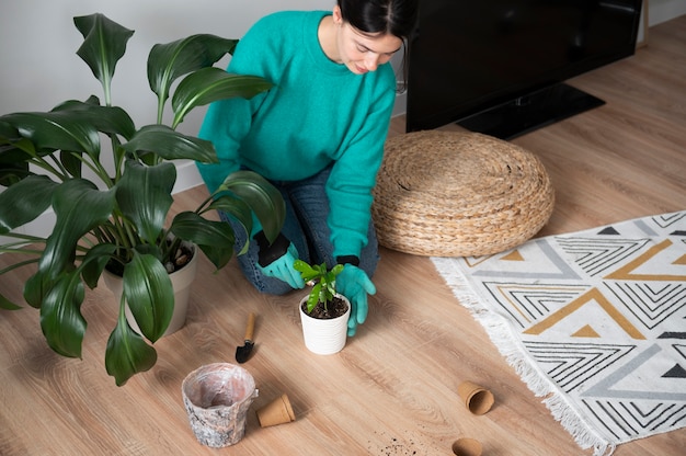 Gratis foto vrouw verwisselt thuis de potten van haar planten tijdens quarantaine