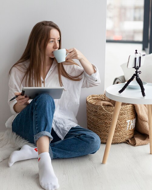 Vrouw vloggen met haar telefoon binnenshuis