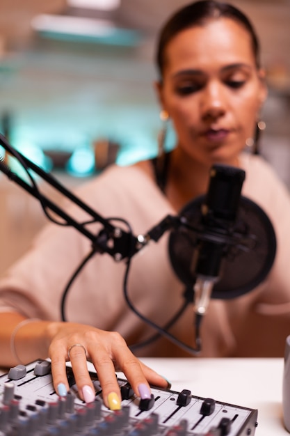 Vrouw vlogger neemt podcast op in thuisstudio verlicht met neonlicht