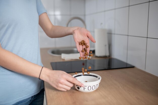 Vrouw vult de keramische voerbak met gepelleteerd voer