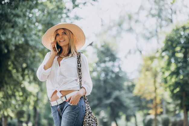 Vrouw wandelen in het park en praten over de telefoon