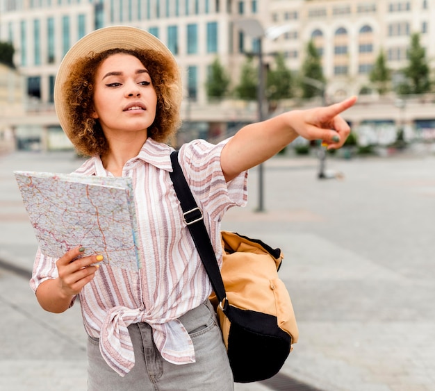 Vrouw wijst in een richting terwijl ze een kaart vasthoudt