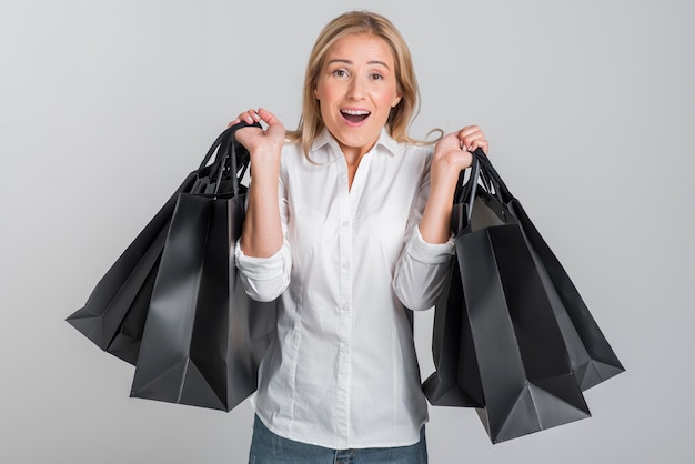 Vrouw wordt overweldigd door de hoeveelheid boodschappentassen die ze vasthoudt