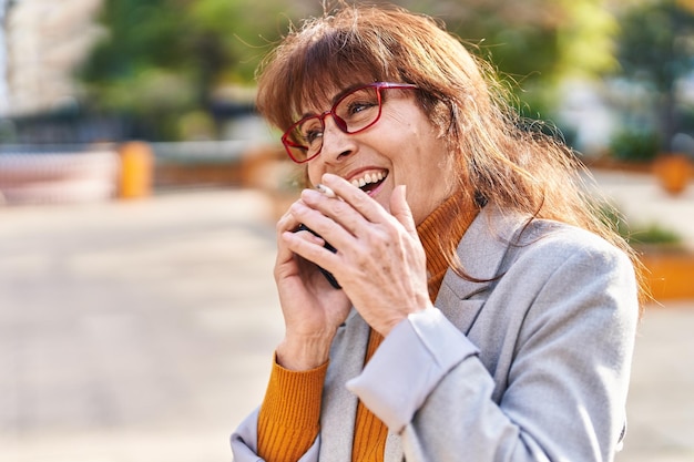 Vrouw zakenman van middelbare leeftijd praten op de smartphone rokende sigaret in het park