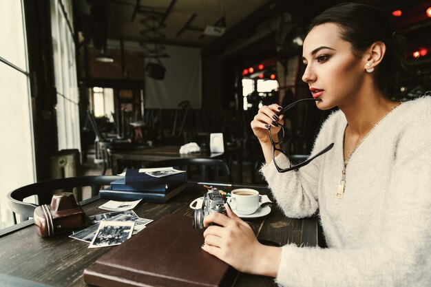 Vrouw ziet er attent zitten aan de tafel met oude foto&#39;s in het café