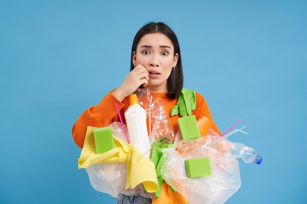Gratis foto vrouw ziet er bang en angstig uit en houdt plastic afval nerveus om op de juiste manier te recyclen