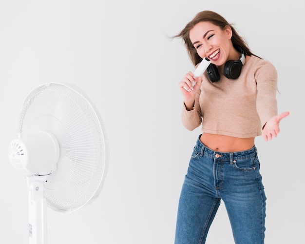 Gratis foto vrouw zingt naast een open ventilator