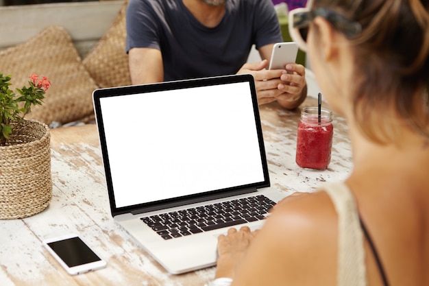 Vrouw zit aan houten tafel bezig met nieuw zakelijk project met behulp van laptopcomputer.