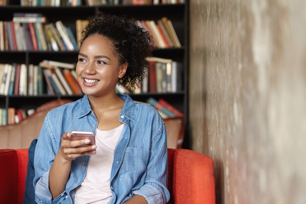 Vrouw zit in een bibliotheek met haar telefoon