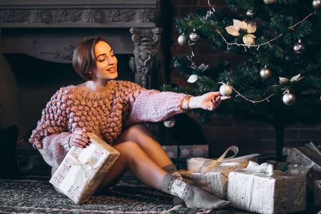 Vrouw zitten door kerstboom omringd met presenteert