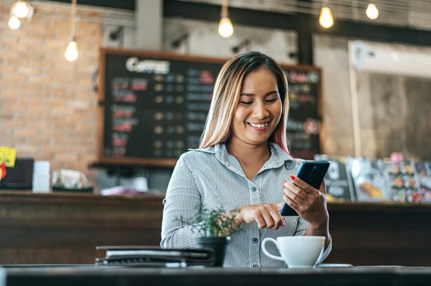 vrouw zitten gelukkig werken met een smartphone in een koffieshop