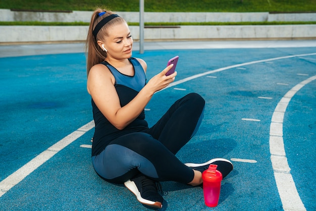 Vrouw zitten op de speelplaats met een telefoon in haar handen