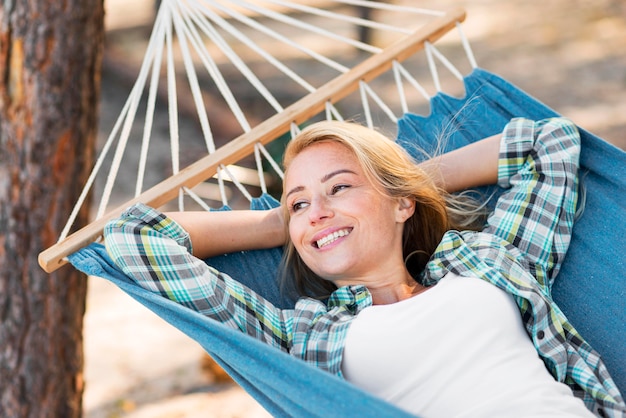 Gratis foto vrouw zittend in een hangmat en wegkijken