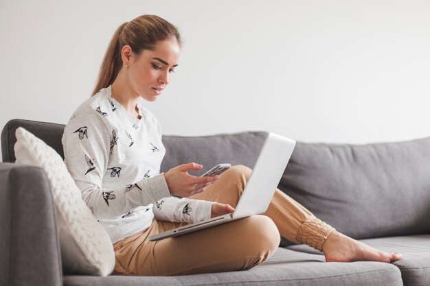 Vrouw zittend op bank met laptop