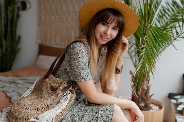 Vrouw zittend op bed in haar boho appartement