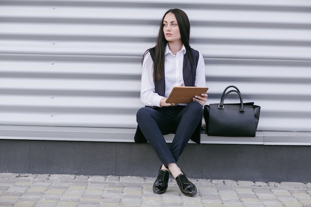 Vrouw zittend op de straat met een tablet in handen