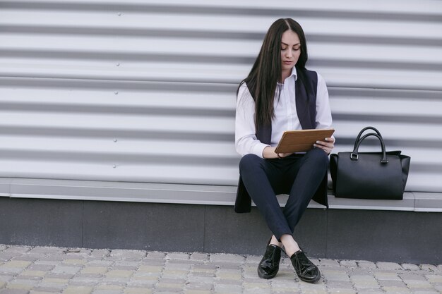 Vrouw zittend op de vloer te kijken naar een tablet