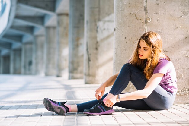 Vrouw zittend op de vloer zetten haar trainers