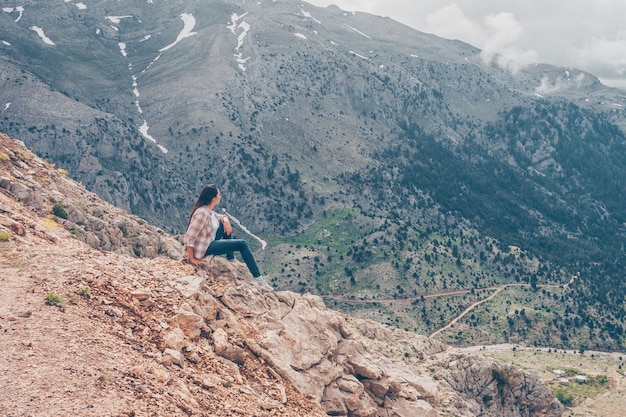 vrouw zittend op rotsen, genieten van het uitzicht en denken in heuvels overdag