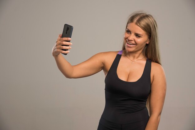 Vrouwelijk model in sportbeha die haar selfie neemt.