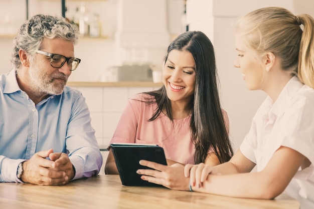 Vrouwelijke agent of manager ontmoeting met een aantal jonge en volwassen klanten, inhoud presenteren op tablet